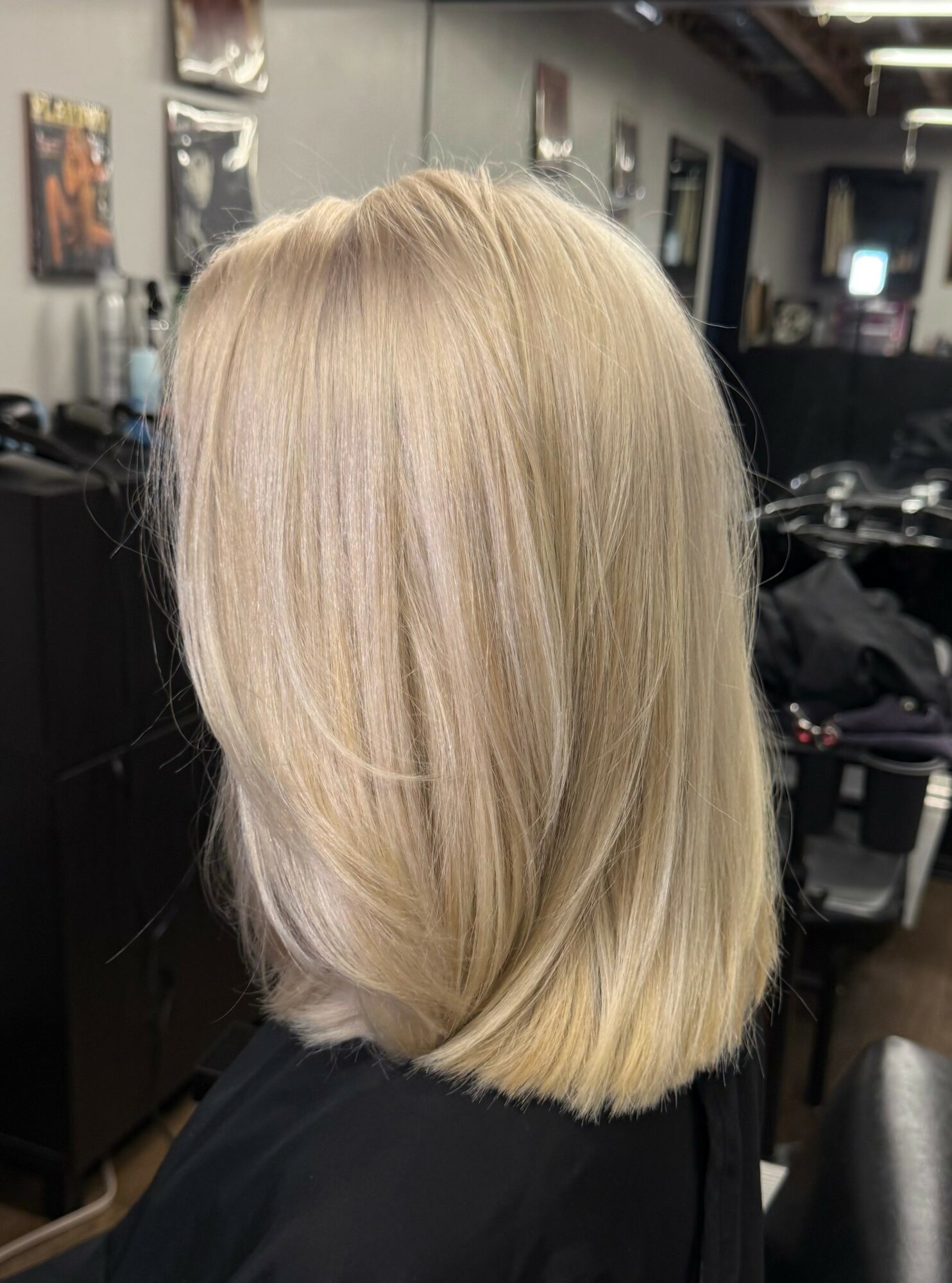Blonde shoulder-length hair with layers, viewed from the back in a salon setting.
