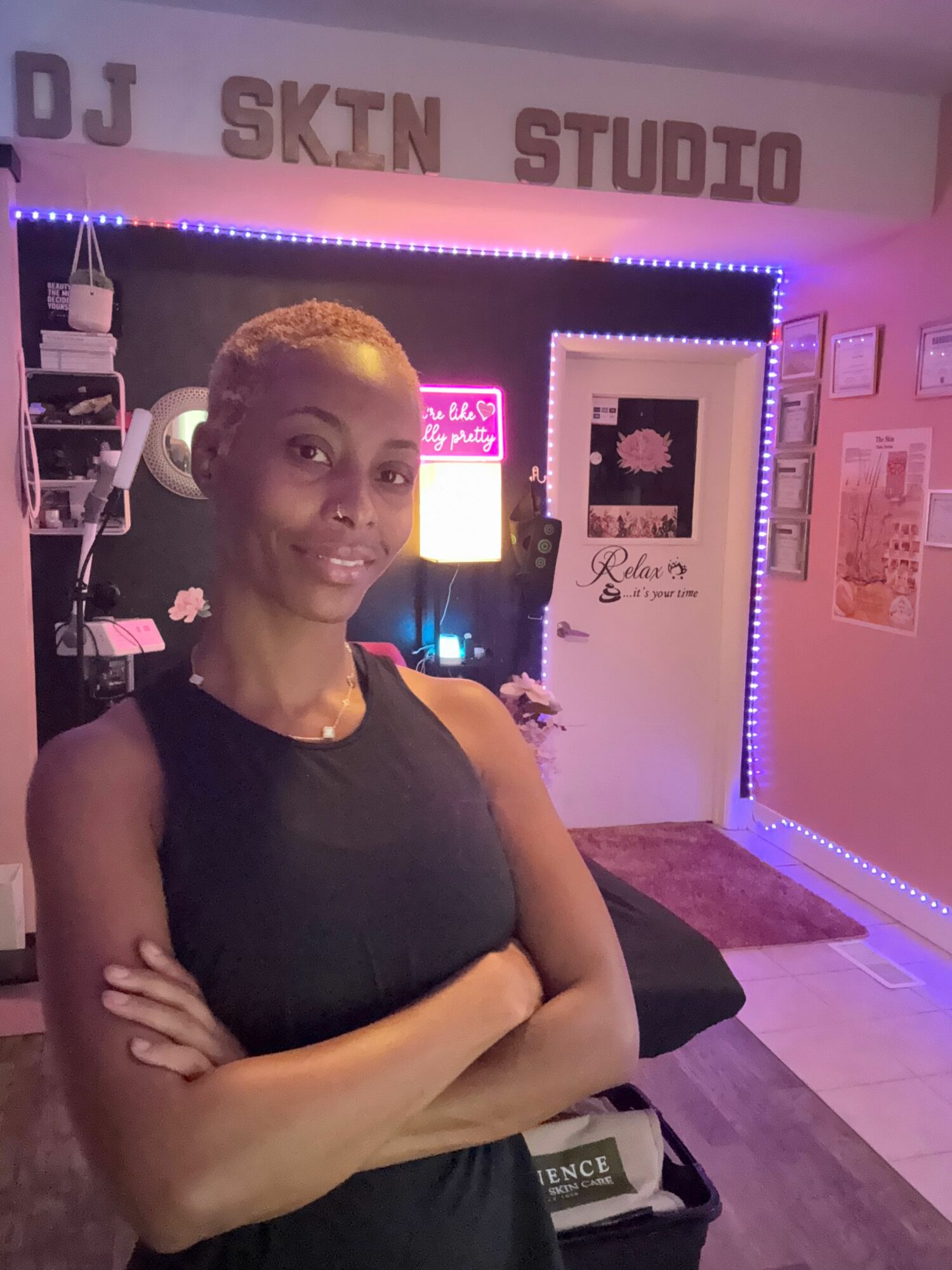Woman with short hair sitting in a recording studio with purple and blue lighting, arms crossed, looking at the camera.