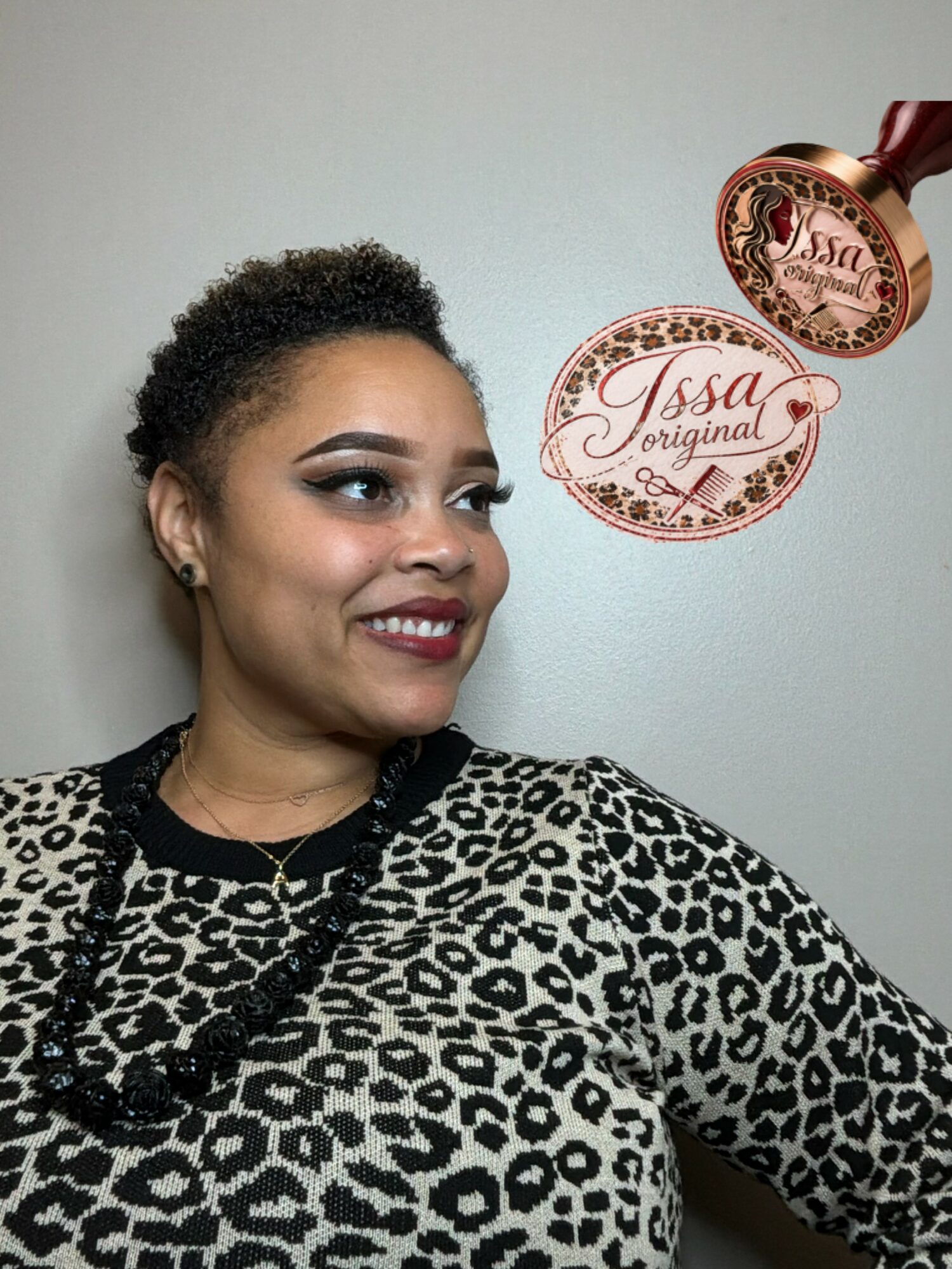 Woman with short curly hair wearing a leopard print top, smiling, holding a circular product label with the text 'Issa Original'.