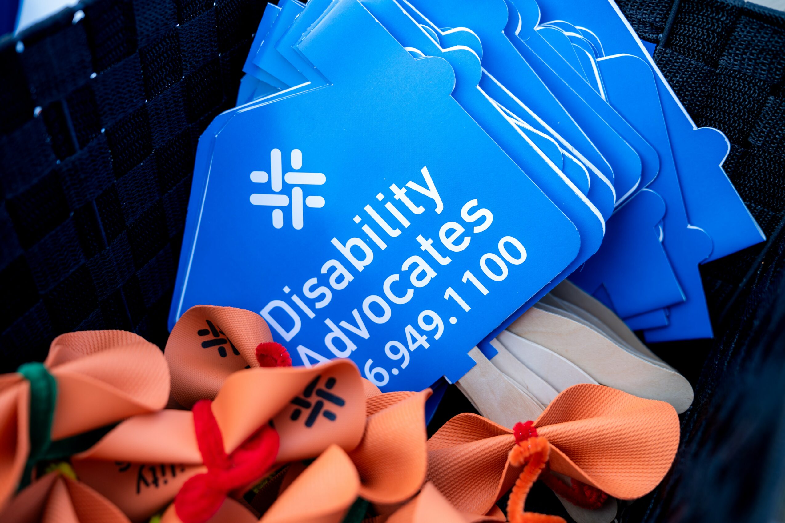 Blue cards with white text reading 'Disability Advocates' and a phone number, stacked on a dark surface.