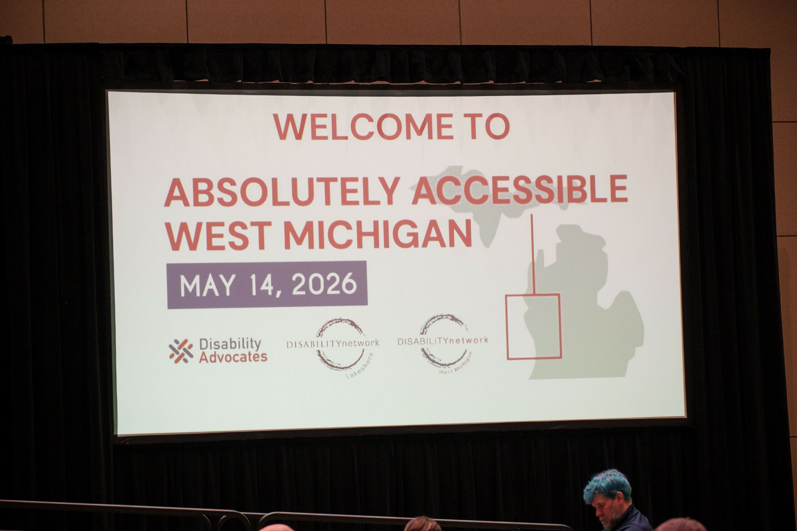 Screen displays welcome message for accessible event in West Michigan, dated May 14, 2026, with logos and a map outline.