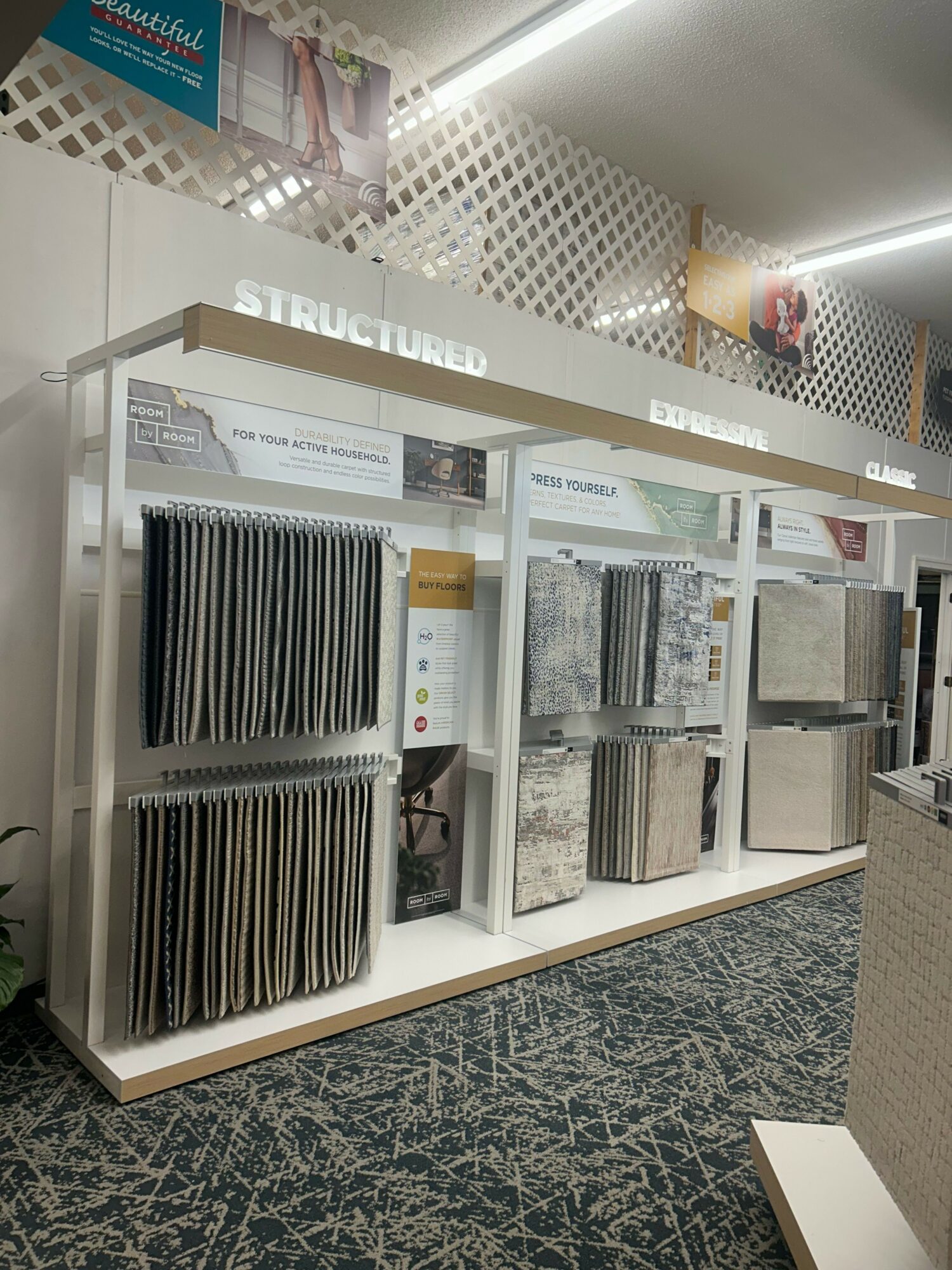 Display shelf with samples and brochures, positioned at an angle, with a patterned floor visible.