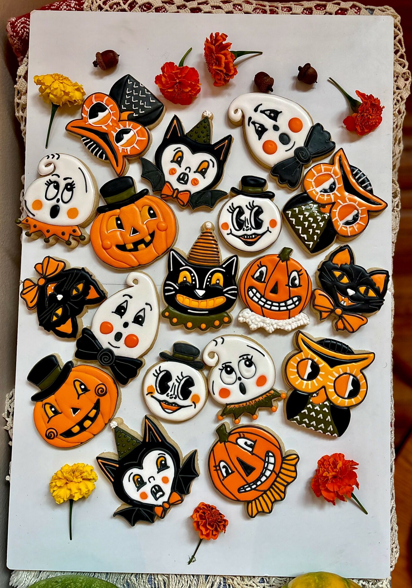 Assorted Halloween-themed cookies with pumpkins, cats, ghosts, and bats on a white surface, decorated with colorful icing and sprinkles.