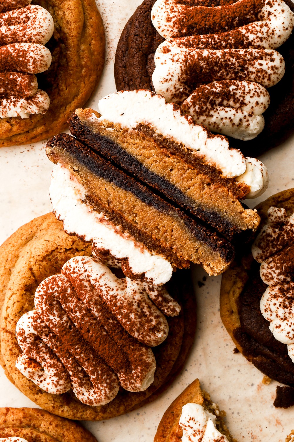 Close-up of a sliced layered cake with cream, chocolate, and sponge layers, surrounded by decorated cookies and biscuits.