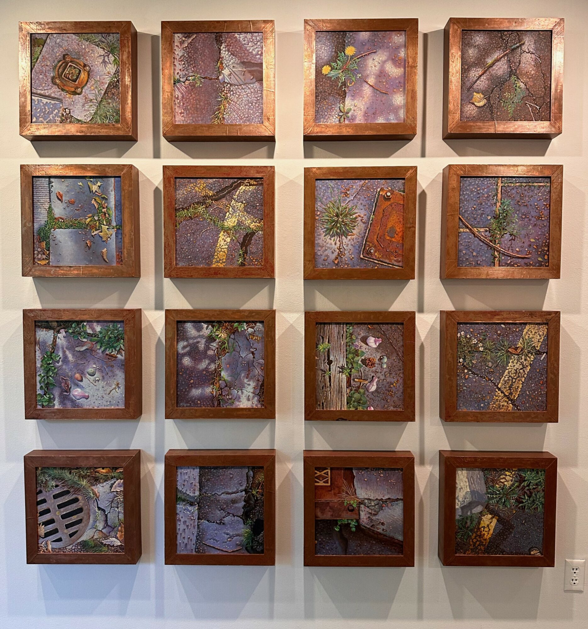 Four rows of four framed abstract artworks with various colors and textures on a wall.
