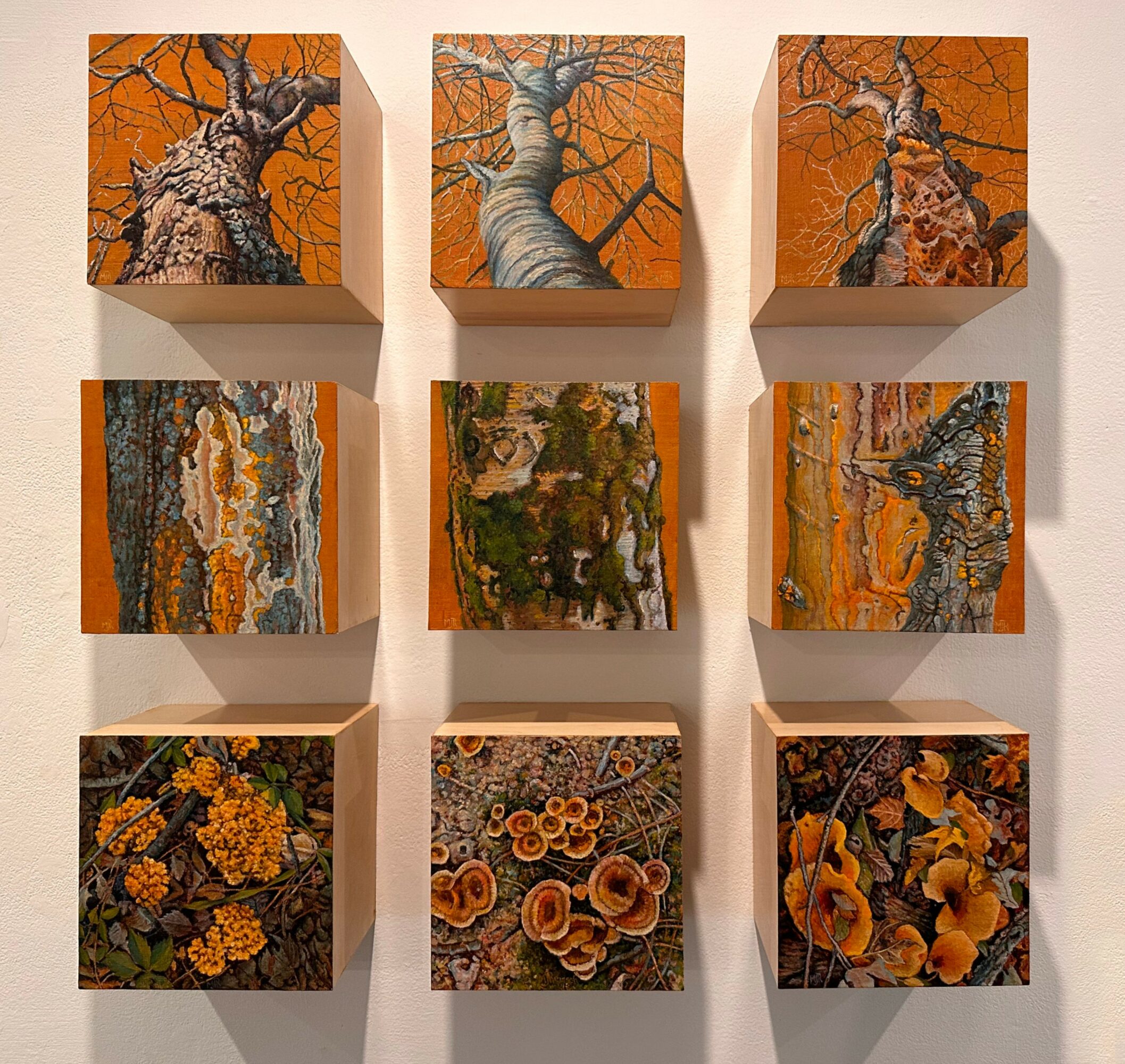 Nine small paintings arranged in a 3x3 grid, featuring trees, landscapes, and floral patterns with warm colors.