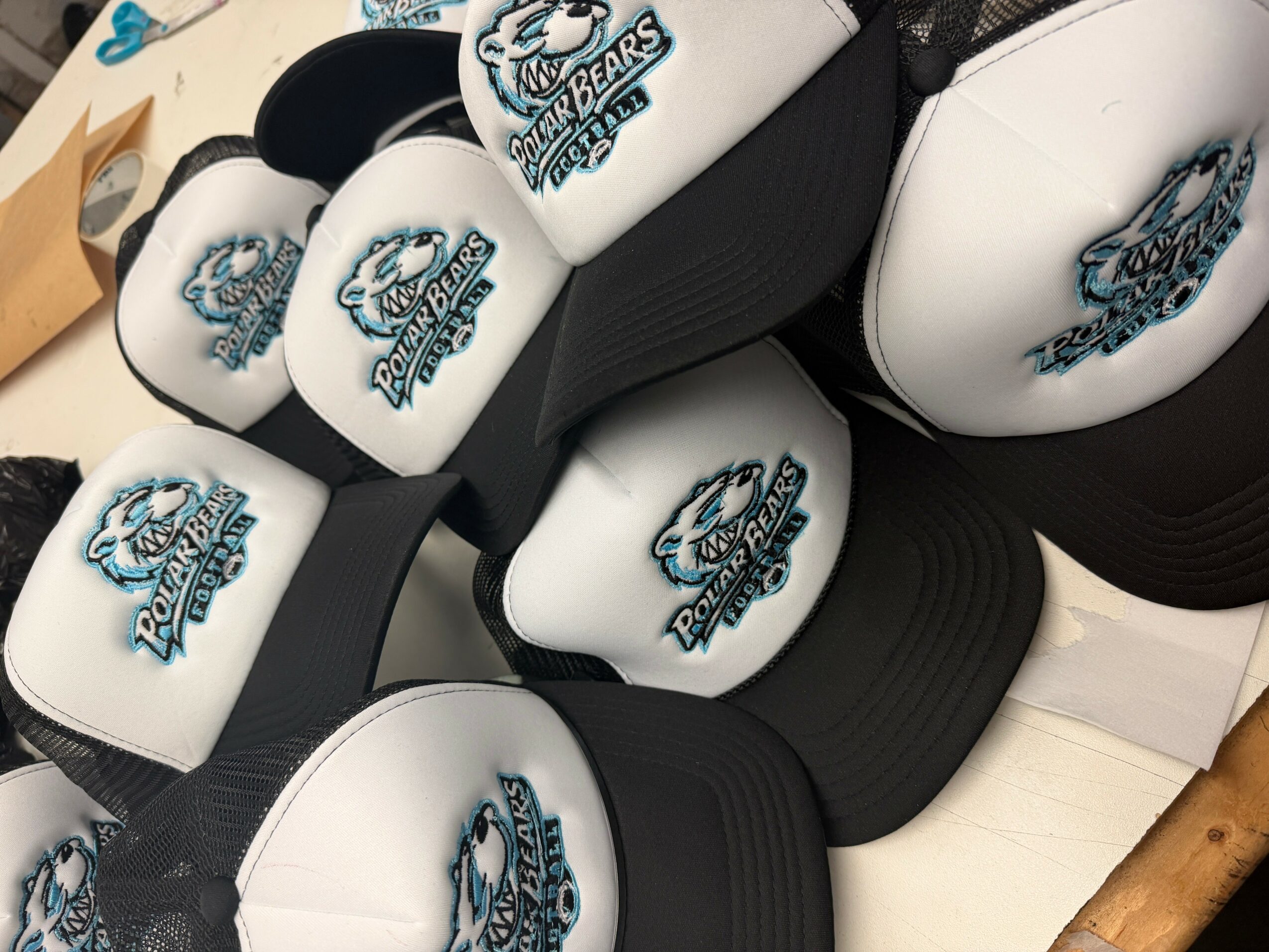 Multiple white and black caps with a logo of a bear and the text 'Lions' on a table.