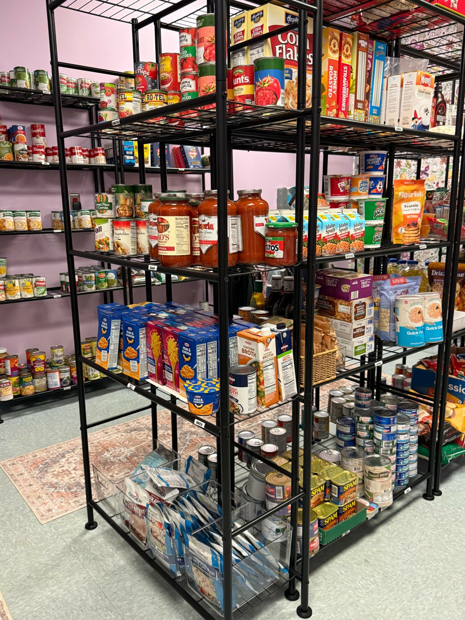 Shelves stocked with various food and beverage products, including bottled drinks and packaged snacks, in a store.