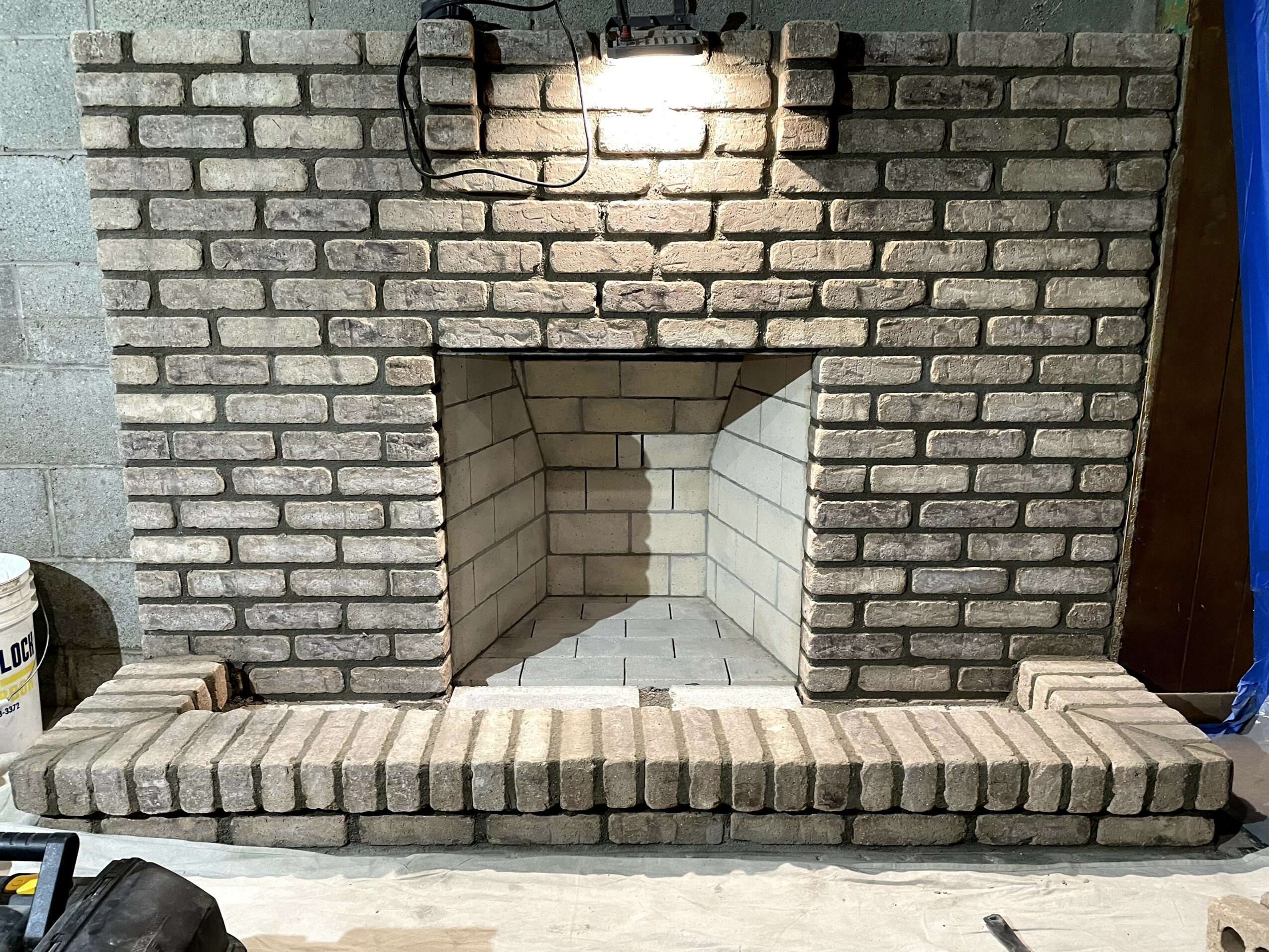 Brick fireplace with a light above, a brick hearth, and a brick interior opening.