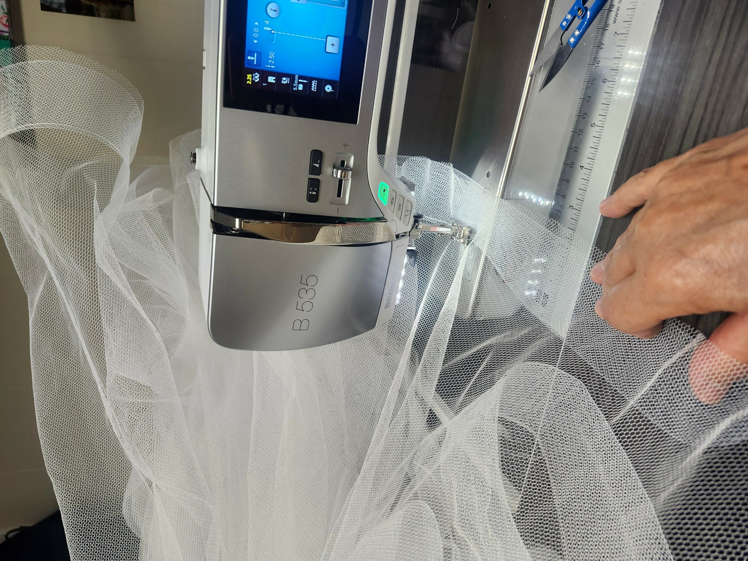 Close-up of a person connecting a medical device with a hand, with a transparent tube and a screen, in a clinical setting.