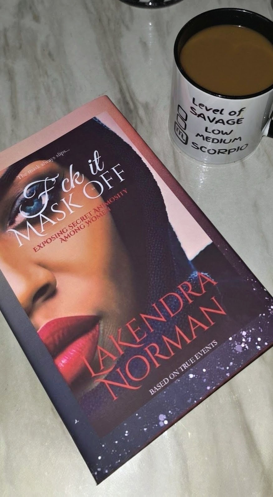 Book titled 'Take It Off' by Takendra Norman with a woman's face on the cover, placed on a table next to a coffee mug.