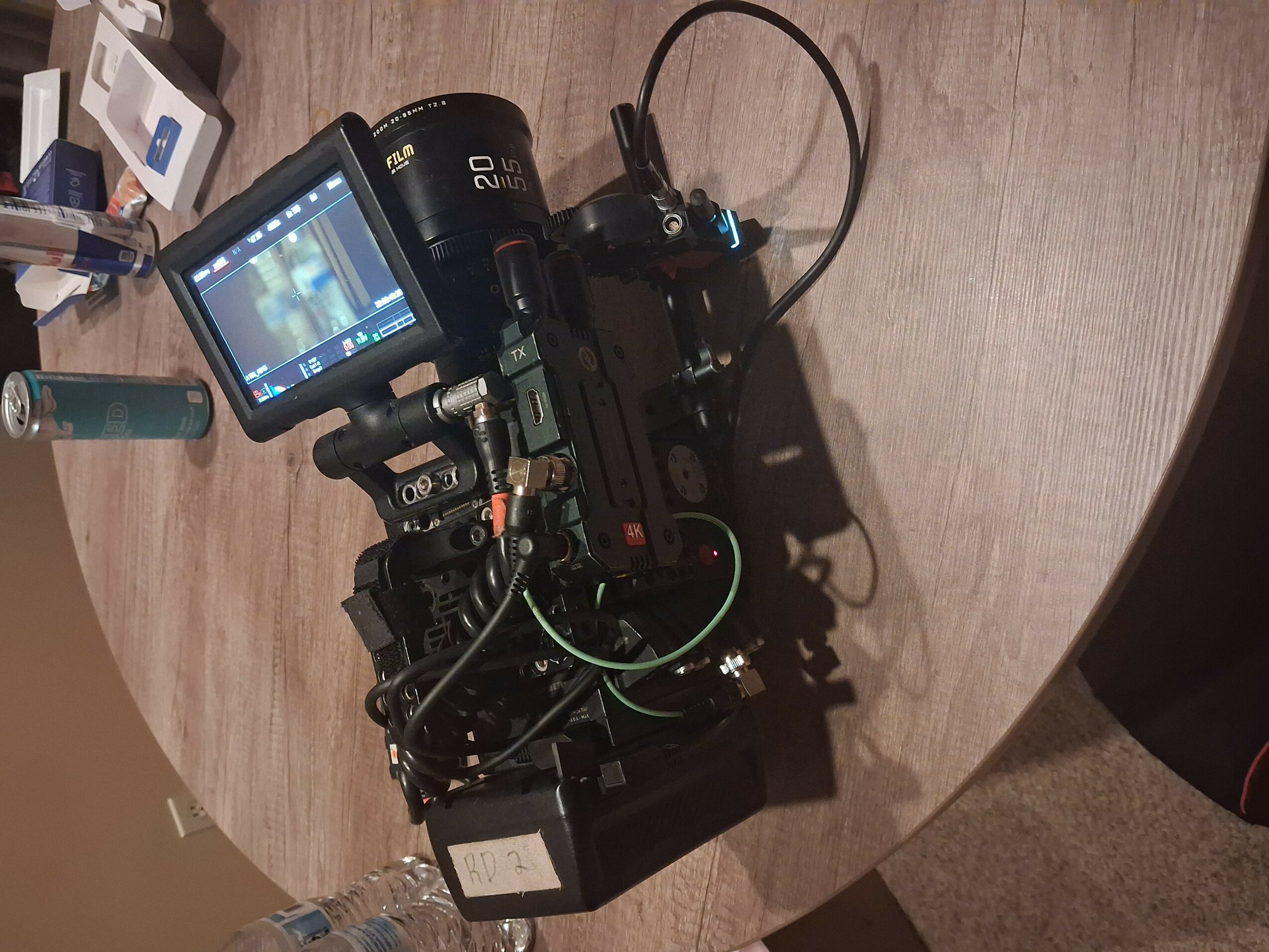 Camera setup on a wooden surface with cables and accessories, viewed from the side.