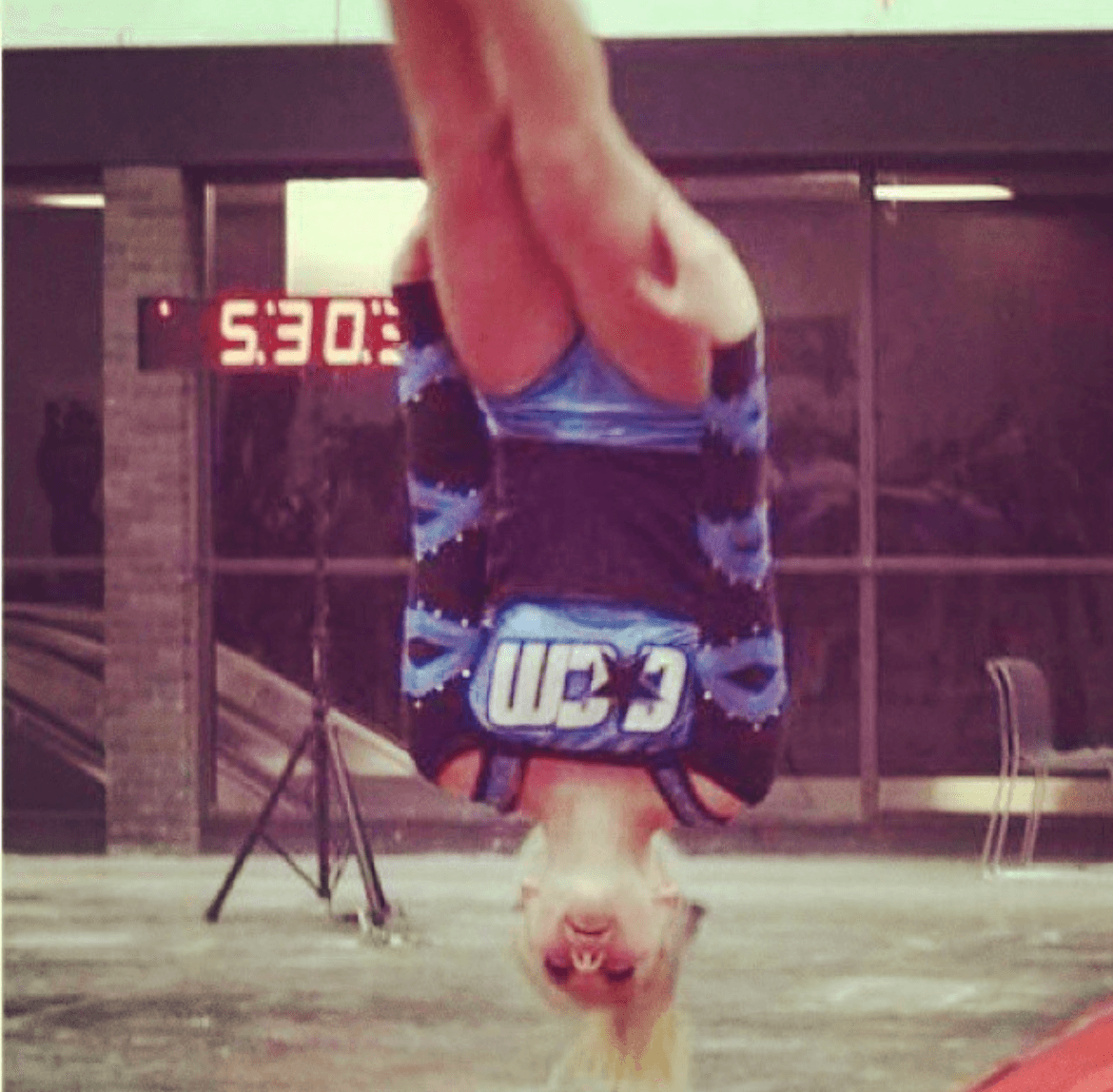 Person doing a handstand indoors, with a digital clock showing 5:30 in the background.